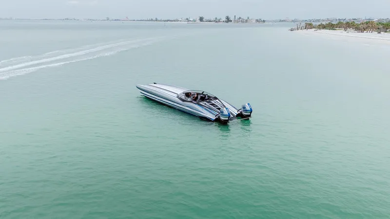  Yacht Photos Pics 2024 MTI 440X boat cruising on calm turquoise waters near a sandy shoreline.
