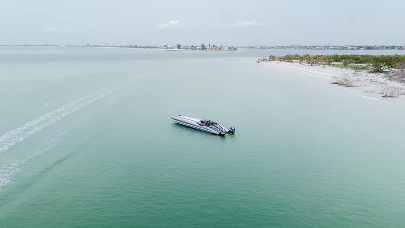  Yacht Photos Pics Aerial view of 2024 MTI 440X boat cruising near a sandy shoreline.