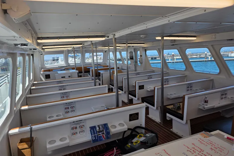 Ocean Thunder Yacht Photos Pics Interior of a 1986 Gulf Craft passenger boat with seating and windows overlooking the water.