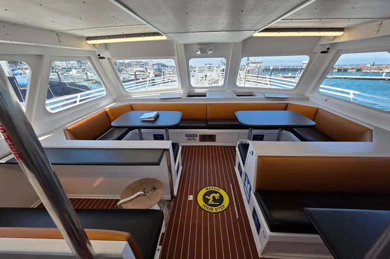 Ocean Thunder Yacht Photos Pics Interior of 1986 Gulf Craft Passenger boat with seating and tables, docked at marina.