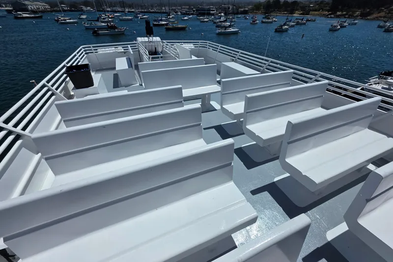 Ocean Thunder Yacht Photos Pics Upper deck of 1986 Gulf Craft Passenger boat with white benches, overlooking marina.