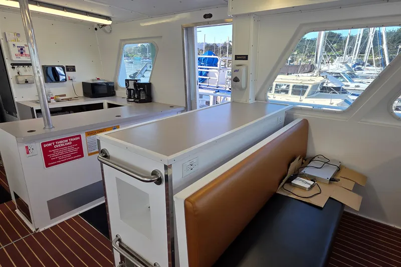 Ocean Thunder Yacht Photos Pics Interior of 1986 Gulf Craft Passenger boat with seating, kitchenette, and marina view.