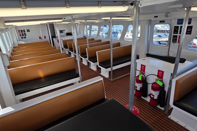 Ocean Thunder Yacht Photos Pics Interior of a 1986 Gulf Craft Passenger boat with brown seating and safety equipment.