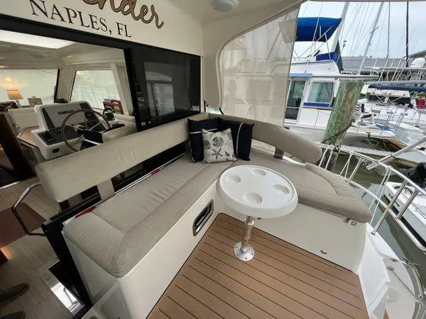 Yacht Photos Pics Luxurious Bavaria E34 Sedan yacht interior with cushioned seating and table, docked in Naples, FL.