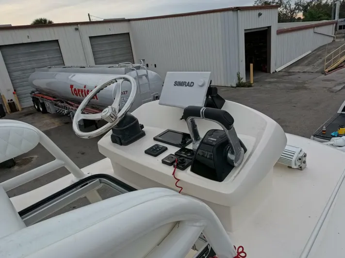  Yacht Photos Pics 2019 Young Boats 27 helm with Simrad electronics and steering wheel, docked near industrial buildings.