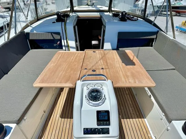 Jessy Yacht Photos Pics 2023 Jeanneau Sun Odyssey 490 cockpit with wooden table and navigation instruments.