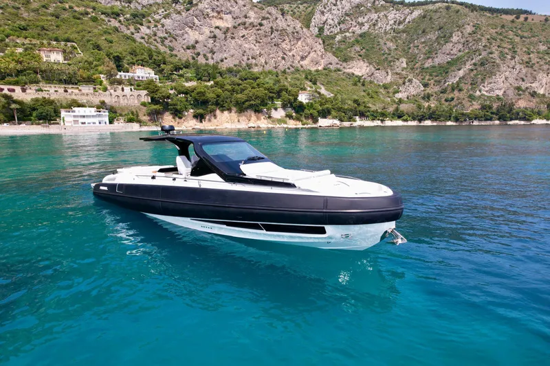 Rebel 47 Yacht Photos Pics 2025 SACS Rebel 47 yacht on clear blue water near rocky coastline.