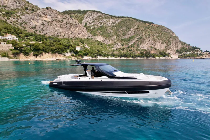 Rebel 47 Yacht Photos Pics 2025 SACS Rebel 47 yacht cruising in clear blue waters near rocky coastline.