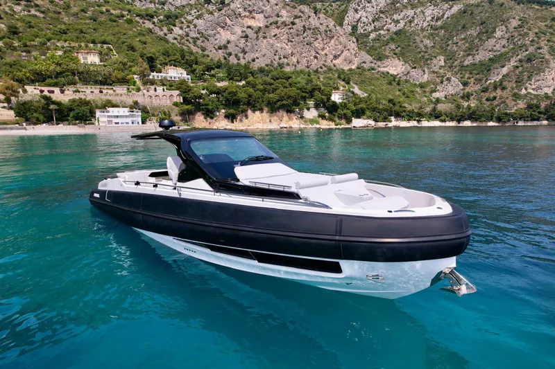 Rebel 47 Yacht Photos Pics 2025 SACS Rebel 47 yacht on clear turquoise water near rocky coastline.