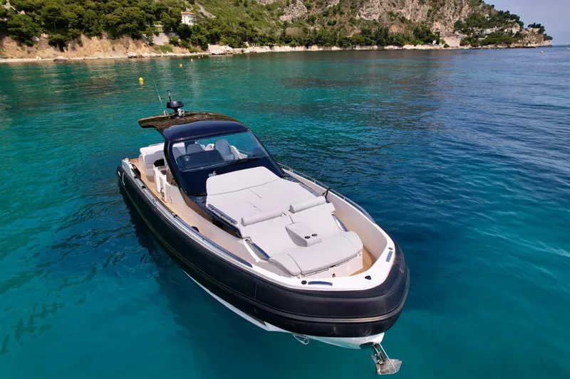 Rebel 47 Yacht Photos Pics 2025 SACS Rebel 47 yacht on clear blue water near a lush coastline.