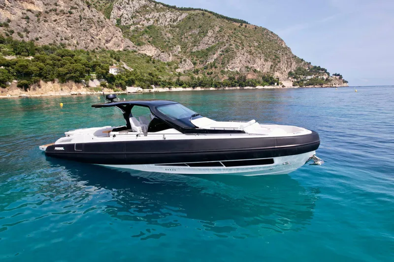 Rebel 47 Yacht Photos Pics 2025 SACS Rebel 47 yacht on clear blue water near rocky coastline.