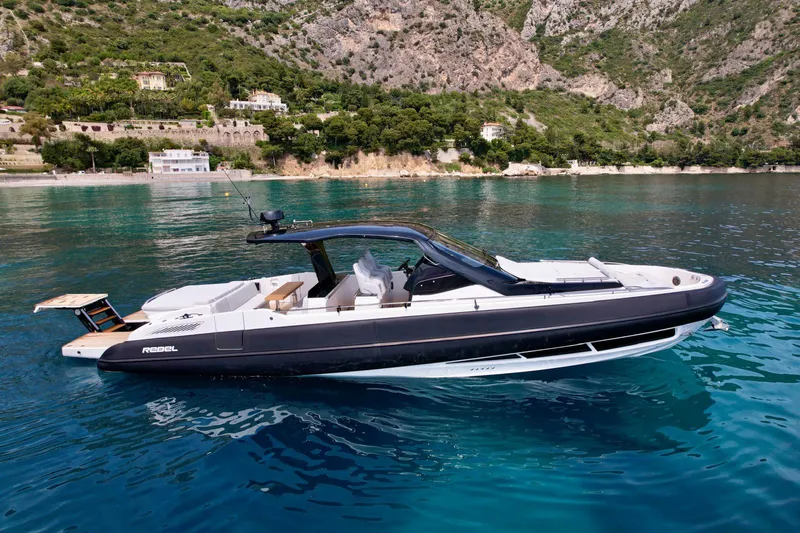 Rebel 47 Yacht Photos Pics 2025 SACS Rebel 47 luxury yacht on clear blue water, scenic coastal backdrop.