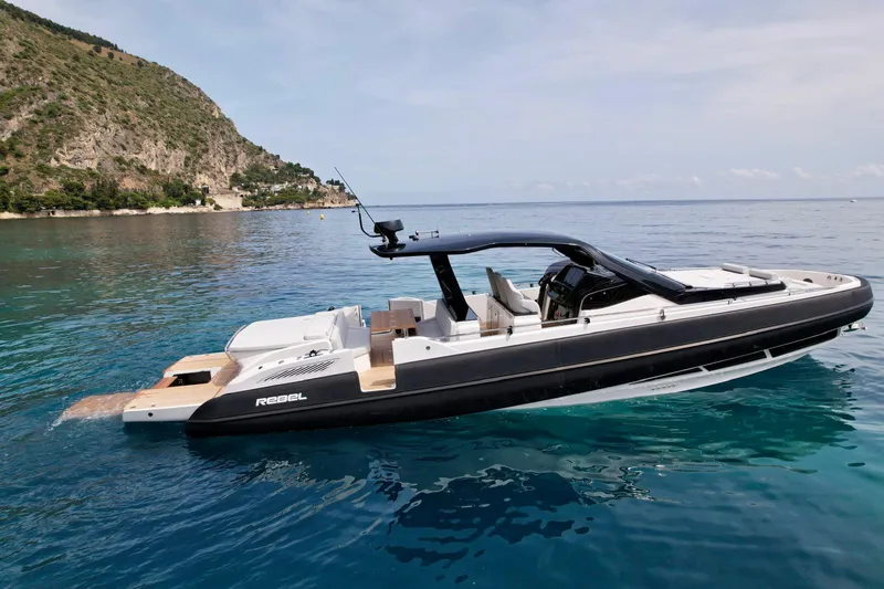 Rebel 47 Yacht Photos Pics 2025 SACS Rebel 47 luxury yacht on clear blue water, coastal backdrop.