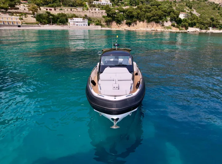 Rebel 47 Yacht Photos Pics 2025 SACS Rebel 47 yacht on clear turquoise water near a scenic coastline.