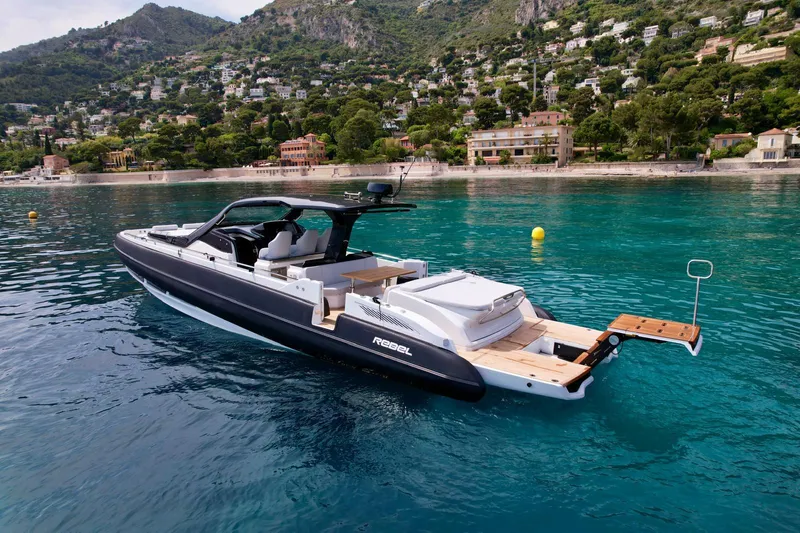 Rebel 47 Yacht Photos Pics 2025 SACS Rebel 47 yacht on clear blue water near a scenic coastline.