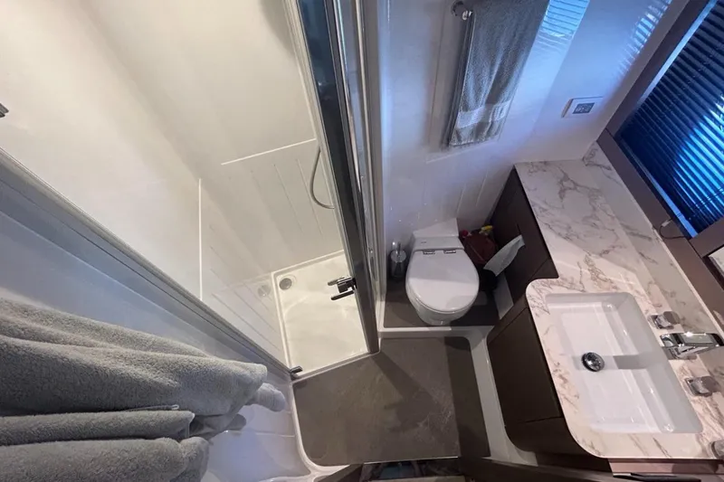  Yacht Photos Pics Luxurious bathroom in 2022 Azimut Magellano 66 yacht with marble countertop and modern fixtures.