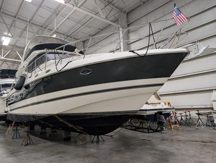 The Last Run Yacht Photos Pics 2003 Cruisers Yachts 5000 Sport Sedan in indoor storage, American flag displayed.