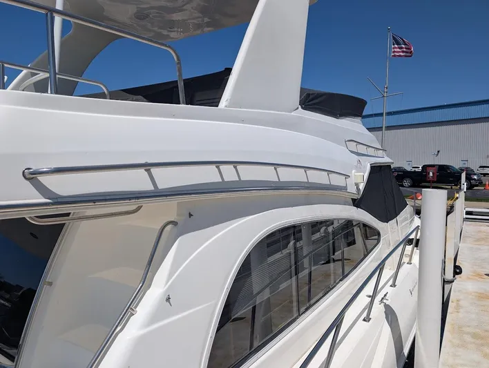 The Last Run Yacht Photos Pics 2003 Cruisers Yachts 5000 Sport Sedan docked, showcasing sleek design and American flag in background.