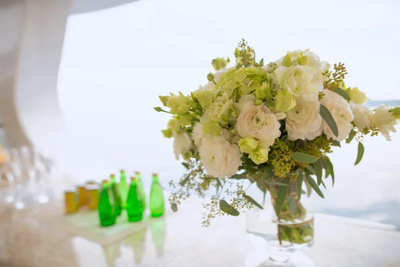 Sama Yacht Photos Pics Elegant floral arrangement on Azimut Grande 35 Metri yacht, 2017, with green bottles in background.