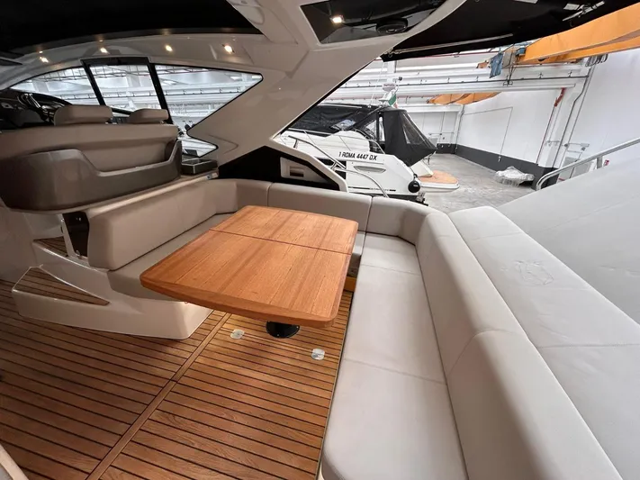  Yacht Photos Pics 2023 Cranchi M 44 HT yacht interior with wooden table and cushioned seating.