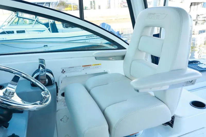 Libres Y Lokos Yacht Photos Pics Captain's seat and helm of 2016 Boston Whaler 285 Conquest boat, featuring sleek design.