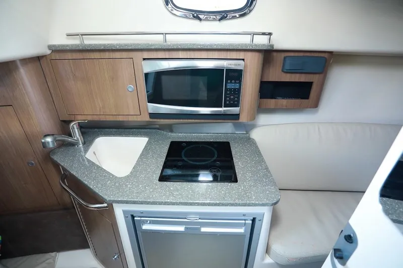 Libres Y Lokos Yacht Photos Pics 2016 Boston Whaler 285 Conquest cabin kitchen with sink, microwave, and stove.