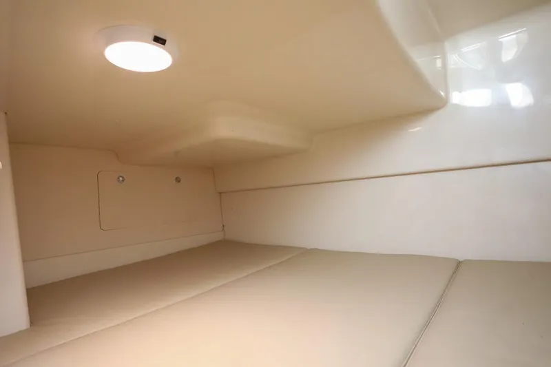 Libres Y Lokos Yacht Photos Pics 2016 Boston Whaler 285 Conquest cabin interior with beige cushions and overhead light.
