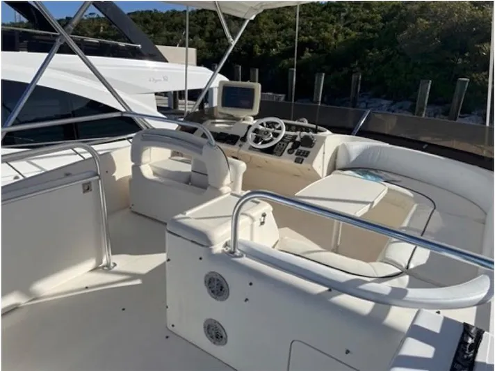  Yacht Photos Pics 1998 Viking Sports Cruiser with spacious cockpit and modern helm, docked near lush greenery.