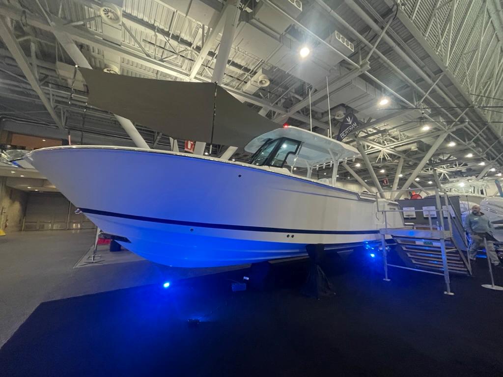 2023 Bertram 28 CC boat displayed indoors with blue accent lighting.