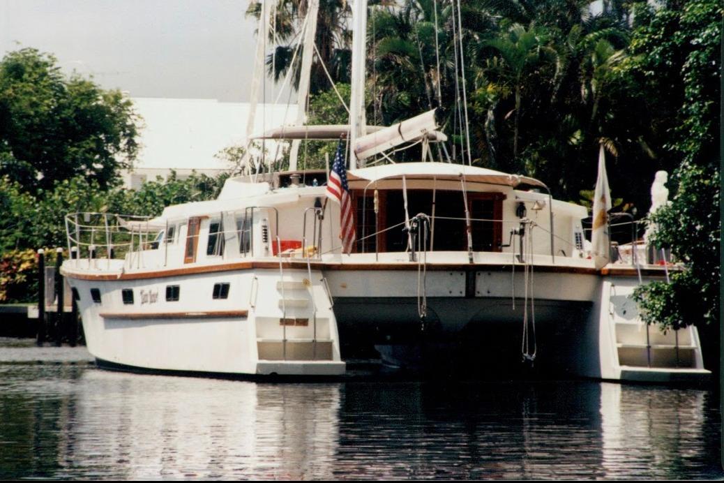 Custom 60 yacht from 1985 docked near lush greenery.