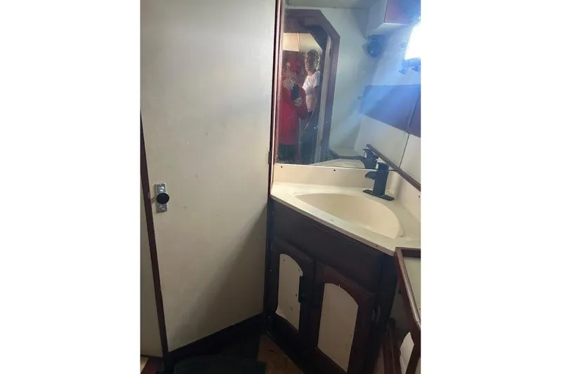Liahona Yacht Photos Pics Small bathroom with sink, mirror, and wooden cabinets in a 1985 Custom model 60.