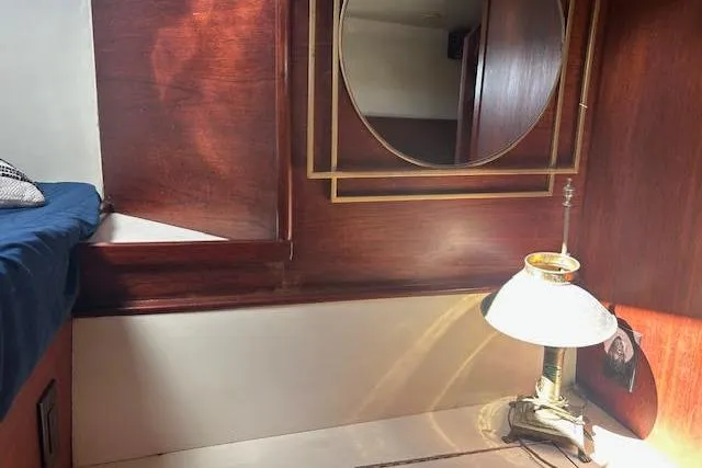 Liahona Yacht Photos Pics Cozy 1985 Custom 60 interior with wooden paneling, round mirror, and vintage lamp.