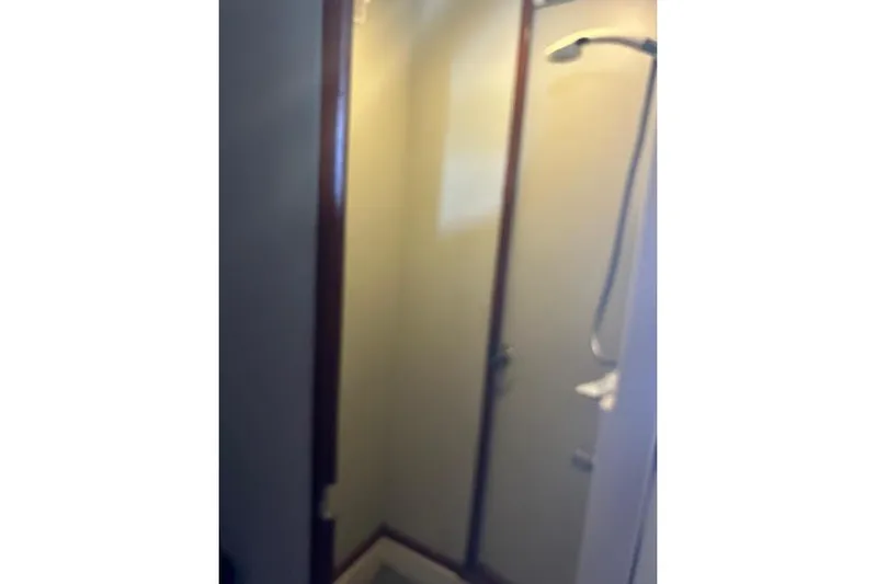 Liahona Yacht Photos Pics Compact shower area in a 1985 Custom 60 model, featuring a glass door and showerhead.