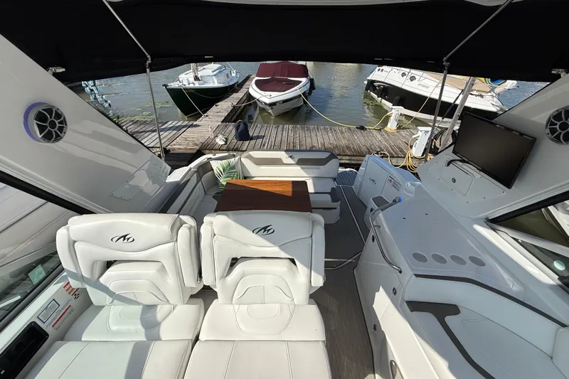  Yacht Photos Pics 2018 Monterey 355 Sport Yacht interior with seating, table, and docked boats in background.