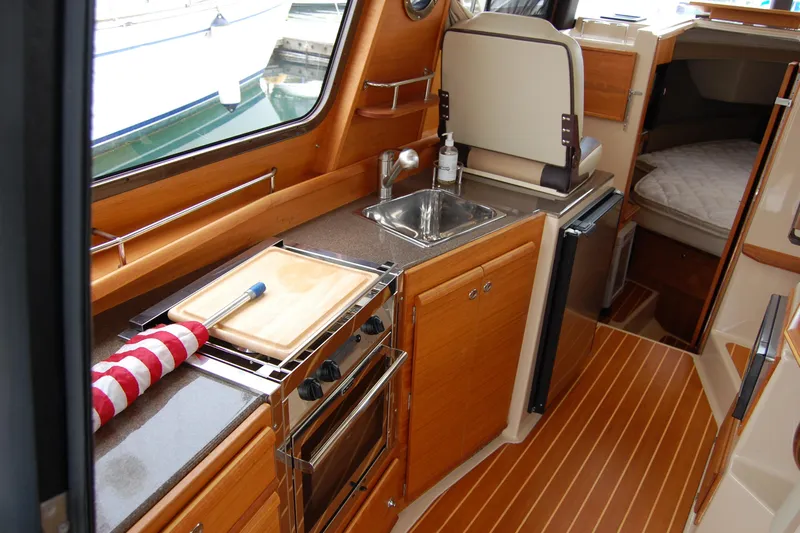  Yacht Photos Pics 2018 Ranger Tugs R29 interior kitchen with wood cabinetry and compact appliances.