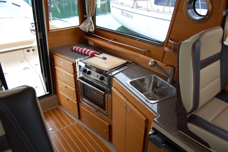  Yacht Photos Pics 2018 Ranger Tugs R29 interior kitchen with stove, sink, and wooden cabinetry.