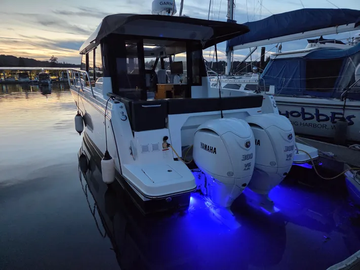  Yacht Photos Pics 2023 Jeanneau NC Weekender 1095 with Yamaha engines, docked at sunset with blue underwater lights.