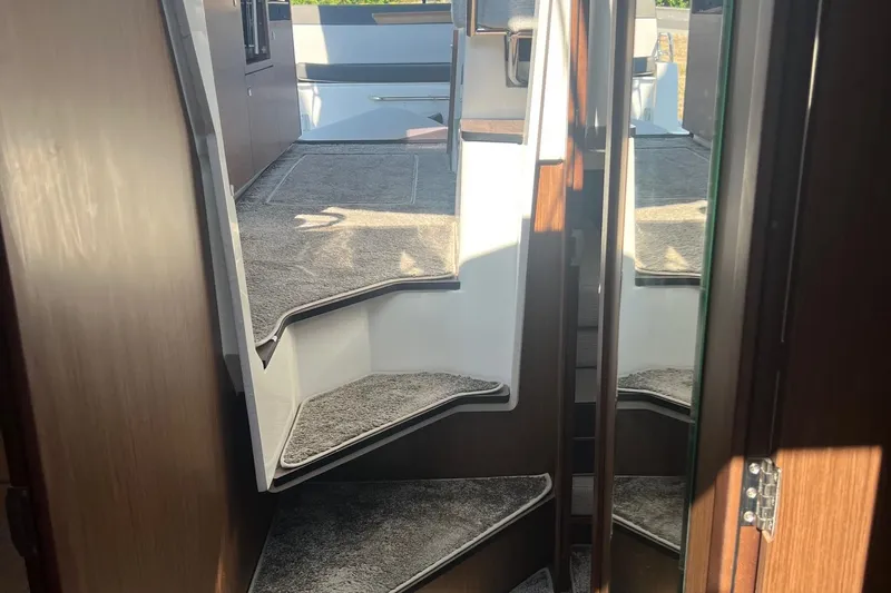  Yacht Photos Pics Interior view of 2023 Jeanneau NC Weekender 1095 with carpeted stairs and wooden accents.