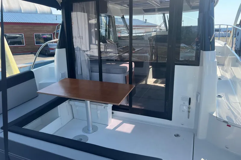  Yacht Photos Pics 2023 Jeanneau NC Weekender 1095 boat with outdoor seating and table, docked at marina.