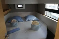 Cozy bedroom in 2018 Nautitech 40 Open catamaran with blue pillows and decorative towels.