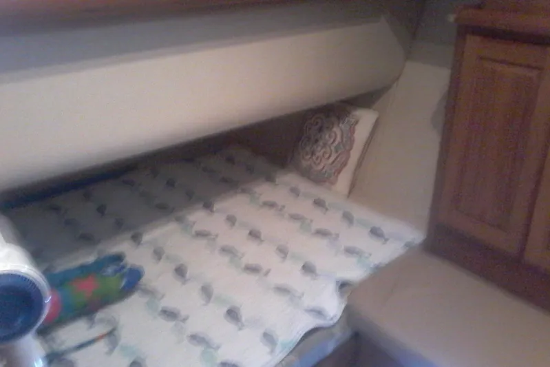 Lusea Yacht Photos Pics 1997 Mainship 350 cabin interior with bed, patterned bedding, and wooden cabinetry.
