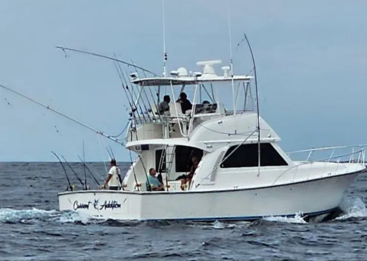 Current Addition Yacht Photos Pics 2006 Henriques 42 Convertible boat on the ocean with fishing rods.