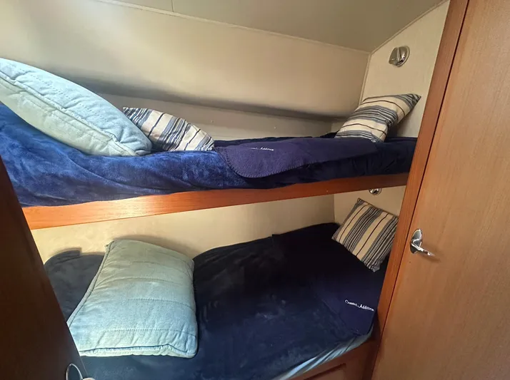 Current Addition Yacht Photos Pics Bunk beds in 2006 Henriques 42 Convertible yacht cabin with blue bedding and striped pillows.