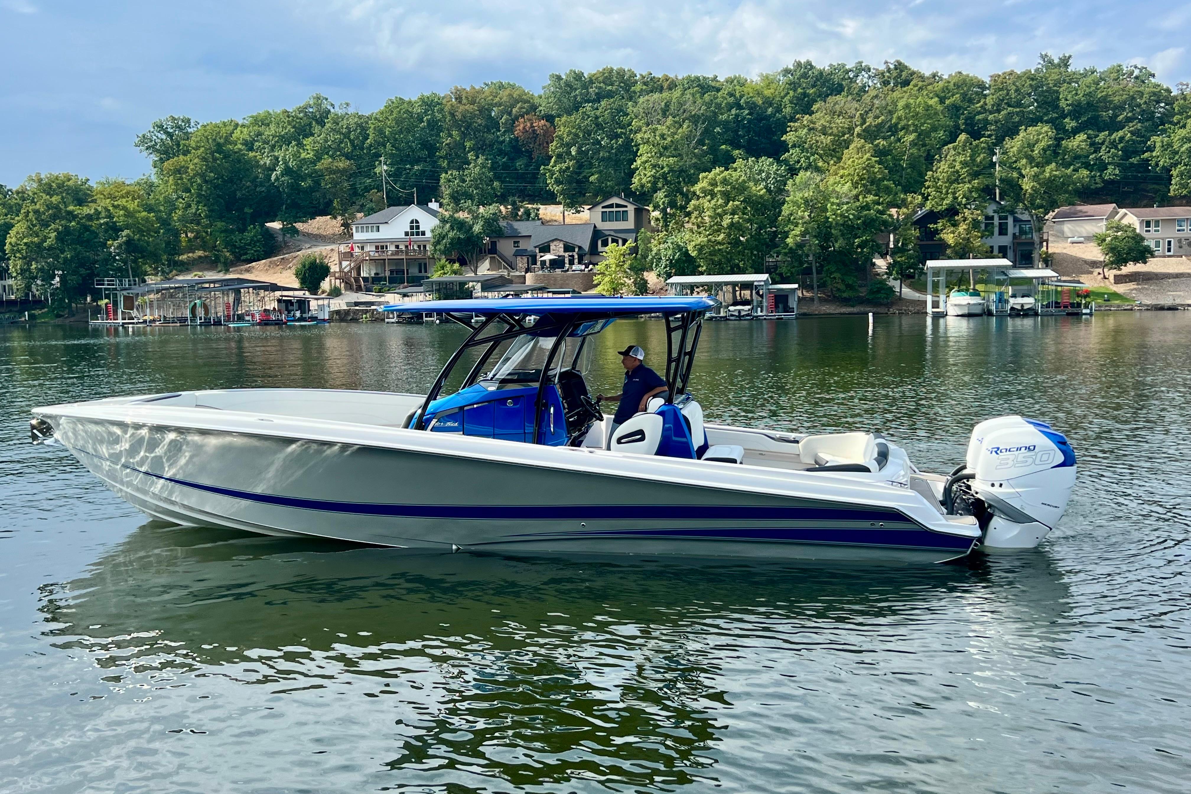 2020 Nor-Tech 340 Sport Center Console boat on a serene lake with lush green shoreline.