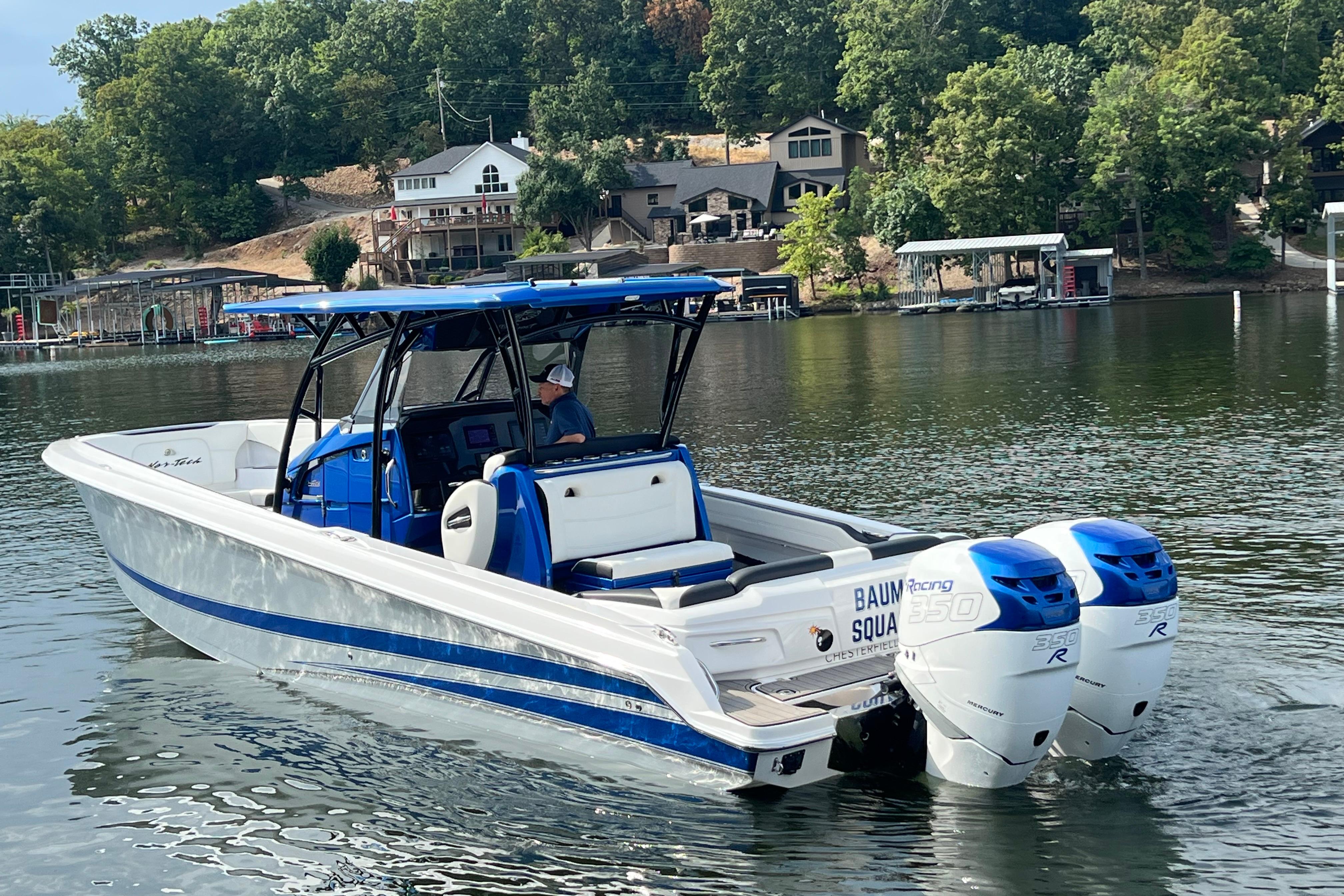 2020 Nor-Tech 340 Sport Center Console boat on a scenic lake with trees and houses.