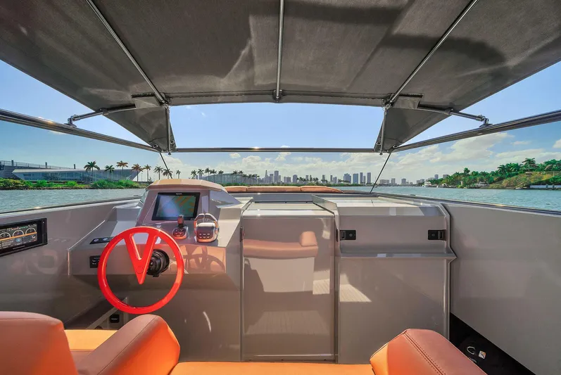 Spectra Yacht Photos Pics Interior view of 2021 Vanquish Yachts VQ 45 with red steering wheel and city skyline.