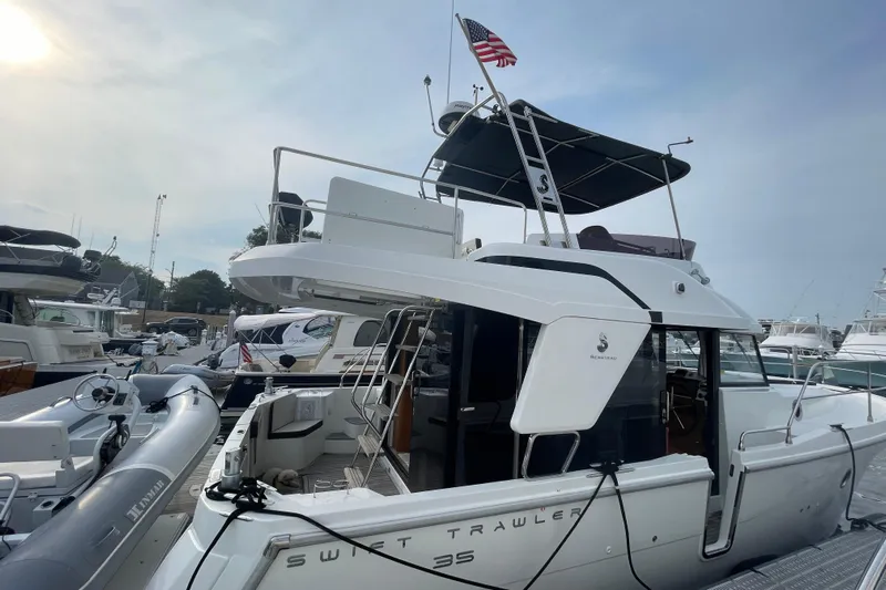 A To Z Yacht Photos Pics 2018 Beneteau Swift Trawler 35 docked, featuring upper deck and American flag.
