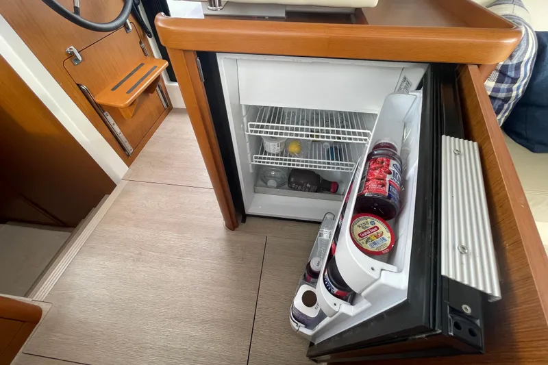 A To Z Yacht Photos Pics Interior of 2018 Beneteau Swift Trawler 35 with open mini fridge and wooden accents.