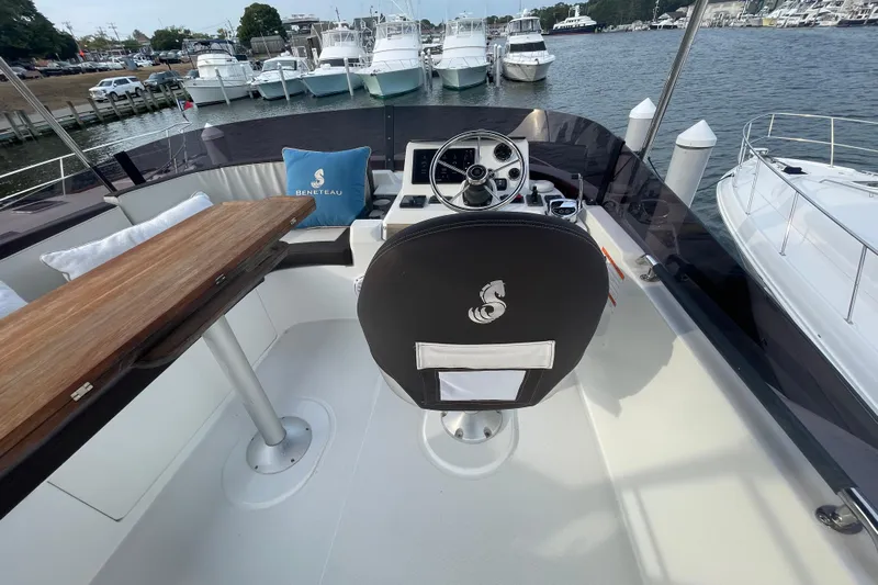 A To Z Yacht Photos Pics 2018 Beneteau Swift Trawler 35 helm with steering wheel, wooden table, and branded cushion.