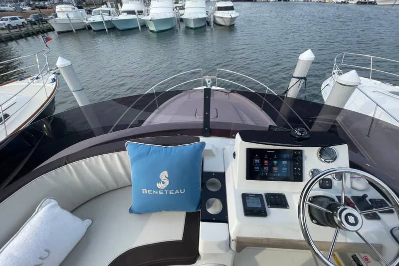A To Z Yacht Photos Pics 2018 Beneteau Swift Trawler 35 helm with navigation controls and branded cushion, docked at marina.